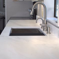 a kitchen counter with a sink, faucet and window in the back ground