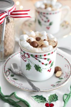 two cups filled with hot chocolate and marshmallows on top of a plate