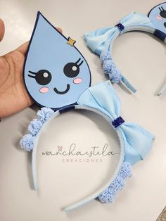 a person holding up two blue headbands with cartoon cats on them and one has a cat's face drawn on it