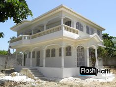 a white two story house with balconies on the first floor and second story