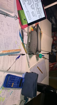 a cluttered desk with papers, pens and a calculator on the table