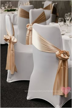 the chairs are decorated with gold sashes and champagne colored bowknots on them