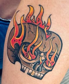 a tattoo on the arm of a man with flames coming out of his skull