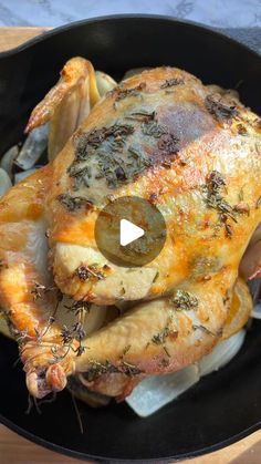 a roasted chicken in a skillet with onions and herbs