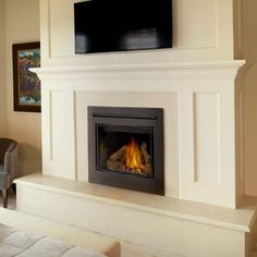 a living room with a fire place in the center and a flat screen tv above it