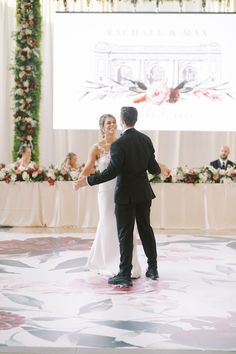 a bride and groom dancing at their wedding reception in front of a large projection screen