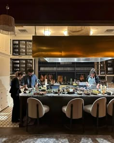 people standing around a table with food on it in a room filled with bookshelves