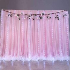 a pink backdrop with flowers and string lights