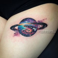 a woman's thigh with a colorful saturn tattoo on her left side, and the planet in the background