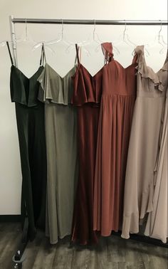 four dresses hanging on a rack in front of a wall