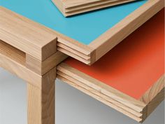 three pieces of wood stacked on top of each other with orange and blue paper underneath them