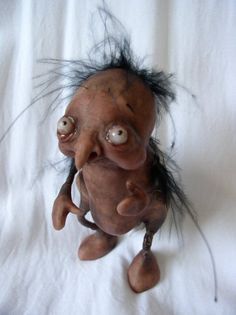 an old troll doll with black hair on a white sheet looking up at the camera