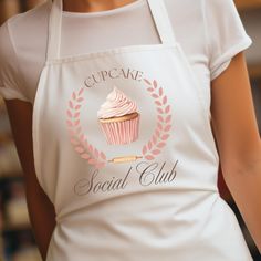 a cupcake with pink frosting on it is being held by a woman in an apron