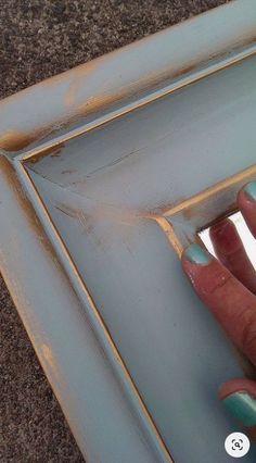 a person's hand is touching the edge of a blue frame with gold trim