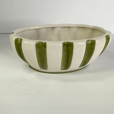 a green and white striped bowl sitting on top of a table next to a wall