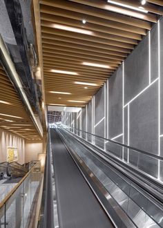 an empty escalator in a building with wooden ceilinging and metal railings