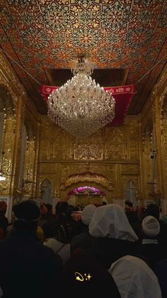 a group of people standing in front of a chandelier inside of a building