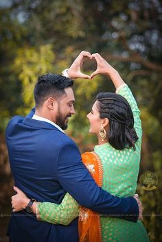 a man and woman holding each other with their hands in the shape of a heart