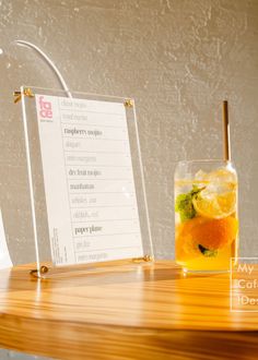 a table topped with a glass filled with orange juice and a sign next to it