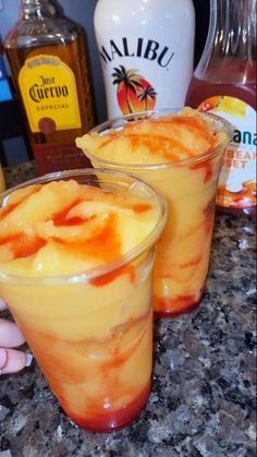 two glasses filled with drinks sitting on top of a counter