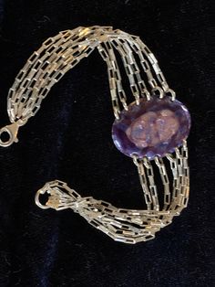 "Unique and handmade sterling silver bracelet with enamel medallion in shades of violet, blue and gold. Slightly domed oval held by slim silver chains fastened by a lobster clasp. 7 1/4\" and 1\" width 13.87g" Oval Polished Chain Bracelet Gift, Silver Oval Chain Bracelet Gift, Oval Polished Chain Bracelet As Gift, Oval Polished Finish Chain Bracelet As Gift, Oval Chain Bracelet With Polished Finish As Gift, Silver Oval Chain Bracelet For Gift, Sterling Silver Oval Chain Bracelet Gift, Oval Sterling Silver Bracelet With Silver Clasp For Gifts, Silver Oval Bracelets For Collectors