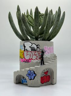 a person standing in front of a potted plant with graffiti on it