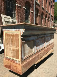 an old wooden box sitting on the side of a road in front of a brick building