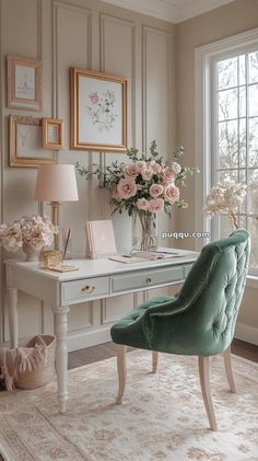 a white desk topped with a green chair next to a vase filled with pink flowers