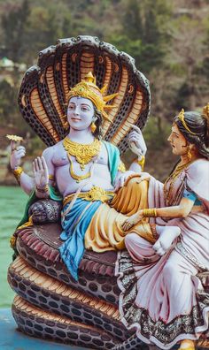 a statue of a woman sitting on top of a boat with a man standing next to her