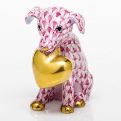 a pink and white dog figurine holding a gold heart shaped object in it's paws