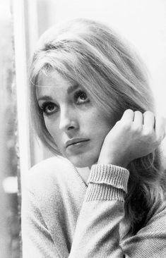 a black and white photo of a woman with her hand on her head, leaning against a wall