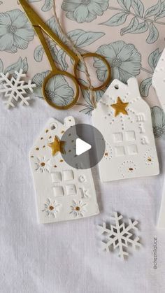 some paper snowflakes and scissors are laying on a table with white fabric, blue flowers and gold stars