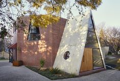 a triangular shaped building with a door and windows on the outside, in front of a tree