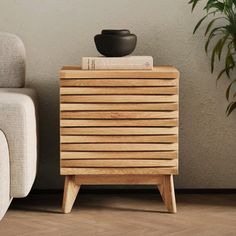 a wooden side table next to a white chair and potted plant on top of it