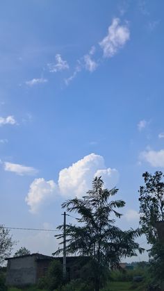 a blue sky with clouds and trees in the foreground