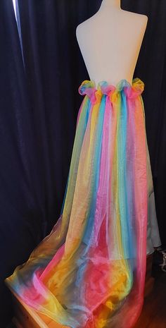 Perfect to finish off your alternative outfit, this handmade blue skirt with a frothy rainbow bustle skirt is ideal for anyone to be worn with pride!! layers of rainbow tulle sweeping out at the back designed to make a impact, finished with matching blue underskirt, laced up at the back for ease with matching ribbons.  waist to hem (back) 39 inches size UK 14.