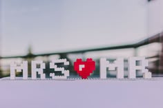 the word mine spelled out with legos in the shape of a red heart on top of a white table