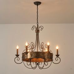 a chandelier with five lit candles hanging from it's center piece in a room