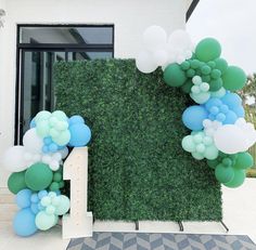 a number one balloon arch in front of a green wall with blue and white balloons