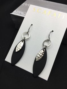 "The almond shaped drop is made of black sea glass and is light weight. The overlapping piece and hoops are plated with a silver alloy. The ear wires are surgical steel with rubber back stoppers to keep the earrings from falling off. All metals used are lead safe. The full length of the earring from the top of the hook down is 2\". Also available is a matching necklace, You have your choice between the following: 1) Sea Glass Black Earrings 2) Sea Glass Necklace- 16\" or 18\" 3) Sea Glass Neckla Modern Black Hypoallergenic Jewelry, Modern Black Jewelry With Ear Wire, Black Hypoallergenic Metal Earrings, Black Minimalist Metal Earrings, Elegant Adjustable Matte Black Jewelry, Elegant Matte Black Adjustable Jewelry, Black Hypoallergenic Dangle Earrings, Black Teardrop Metal Jewelry, Nickel-free Black Dangle Jewelry