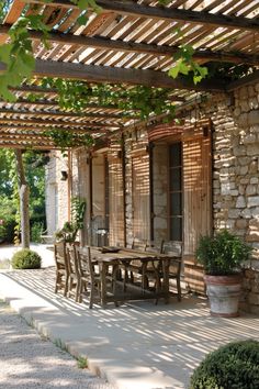 an outdoor dining table and chairs under a pergolated roof