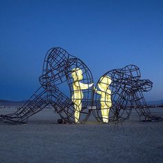 a large metal sculpture sitting on top of a sandy beach next to a blue sky