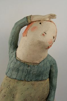 a ceramic sculpture of a person with a bird on his head and hands in the air