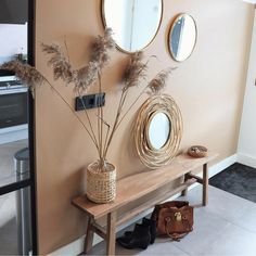 a wooden bench sitting next to a wall with mirrors and plants on top of it