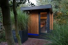 an outdoor sauna in the middle of some trees and grass with its door open