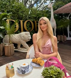 a woman sitting at a table in front of a giraffe statue and food