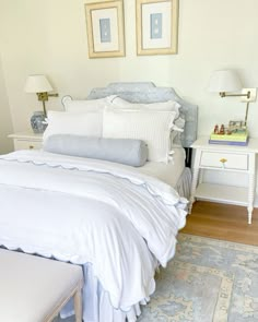 a white bed sitting in a bedroom next to two framed pictures