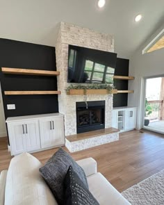 a living room with white furniture and a flat screen tv mounted on the wall above a fireplace