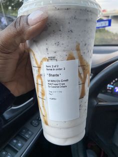 a person holding up a drink in their hand while sitting in the driver's seat