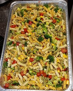 a pan filled with pasta and vegetables on top of a stove